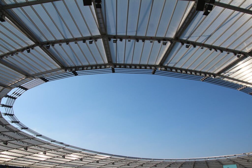 A modern stadium roof design framing a clear blue sky, illustrating structural elegance and openness.