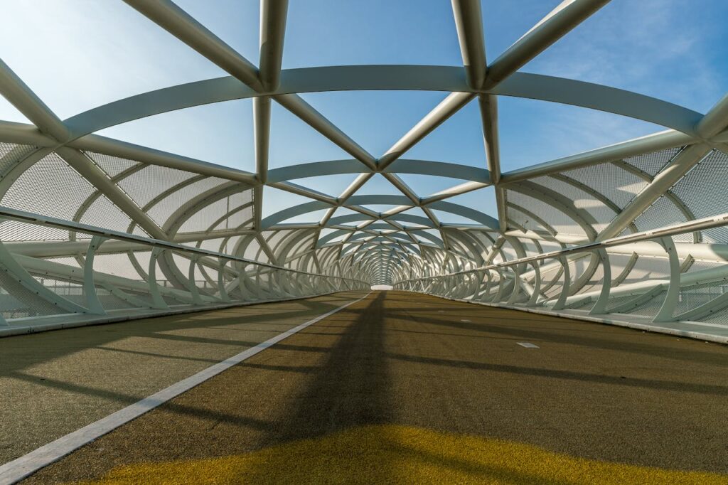 Innovative steel bridge structure featuring geometric designs and modern architecture on a sunny day.